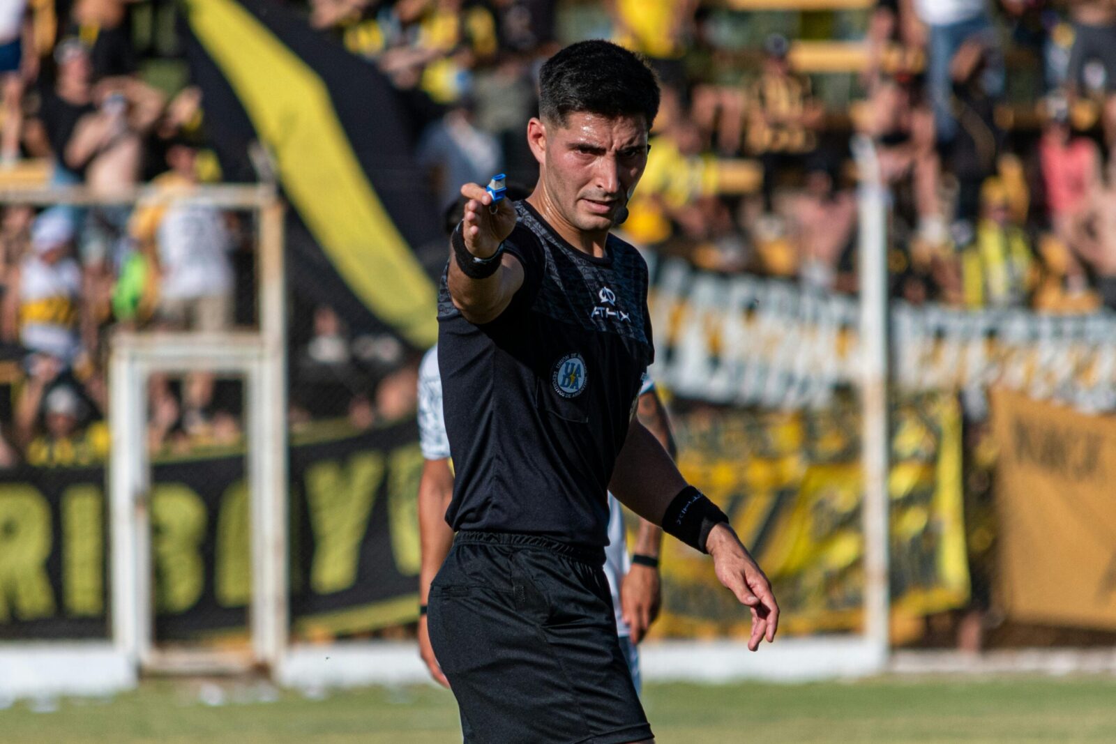 Soccer referee signaling a decision during an intense game outdoors.